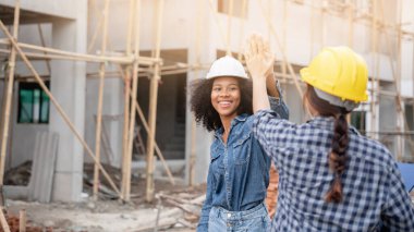 Mühendis ve ustabaşı inşaat işçileri inşaat alanında el sıkışıyor.