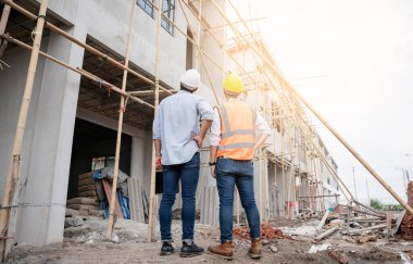 Mühendis ve ustabaşı çeşitli işlevleri kontrol etmek için inşaat alanındaki projeleri tartıştılar ve işaret ettiler..