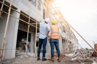 Mühendis ve ustabaşı çeşitli işlevleri kontrol etmek için inşaat alanındaki projeleri tartıştılar ve işaret ettiler..