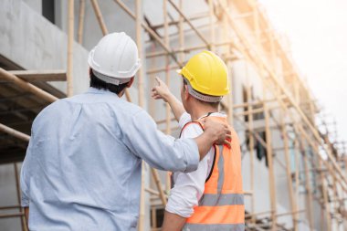 Mühendis ve ustabaşı çeşitli işlevleri kontrol etmek için inşaat alanındaki projeleri tartıştılar ve işaret ettiler..
