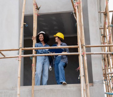 Mühendis ve kadın ustabaşı çeşitli işlevleri kontrol etmek için inşaat alanında duruyorlar..