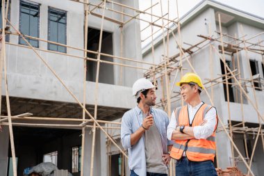 Mühendis ve ustabaşı çeşitli işlevleri kontrol etmek için inşaat alanındaki projeleri tartıştılar..