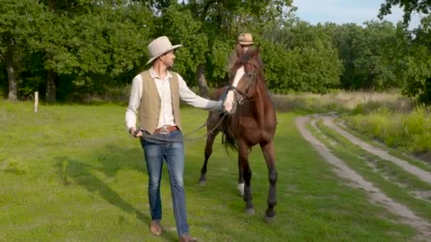 Un joven vaquero lleva un caballo en el que su hija está sentada. — Vídeos de Stock