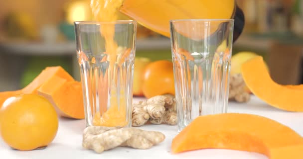 El batido de calabaza y jengibre se vierte en vasos sobre un fondo de verduras y frutas frescas. — Vídeos de Stock