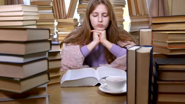 Дівчина читає книгу в бібліотеці — стокове відео