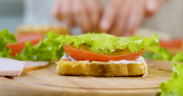 Chef femenino en la cocina de la casa recoge un sándwich — Vídeo de stock