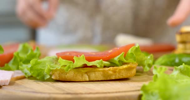 Chef femenino en la cocina de la casa recoge un sándwich — Vídeo de stock