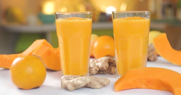 Pompoen en gember smoothie wordt gegoten in glazen tegen een achtergrond van verse groenten en fruit. — Stockvideo