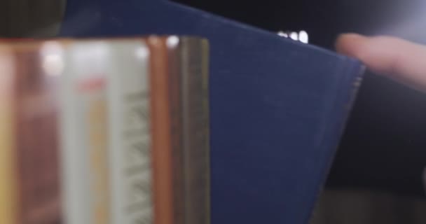 Рука чоловіка шукає правильну книгу серед колекції томів — стокове відео