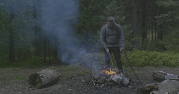 Бородатый мужчина турист у костра в лесу. — стоковое видео