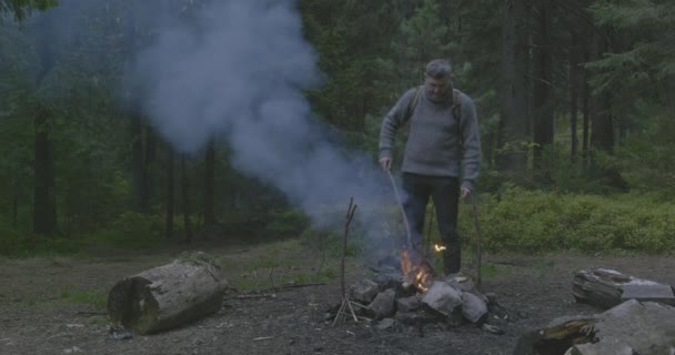 Vousatý turista u ohně v lese. — Stock video