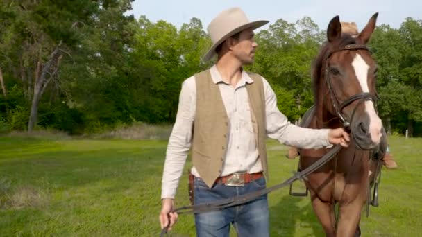 A young cowboy is leading a horse on which his daughter is sitting — Stock Video