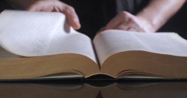 Adam ders kitabının sayfalarını çeviriyor.