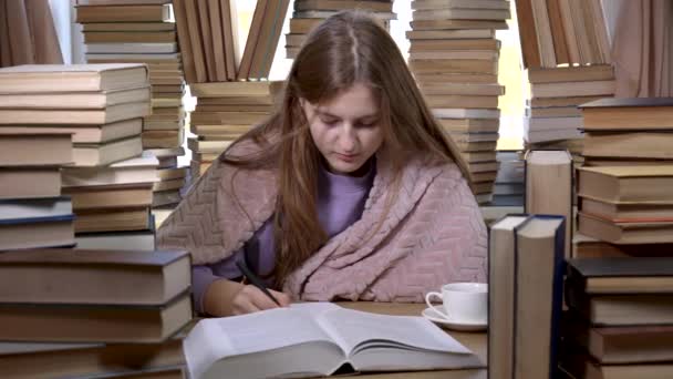 Una chica lee un libro en la biblioteca — Vídeos de Stock