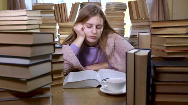 Девушка читает книгу в библиотеке — стоковое видео