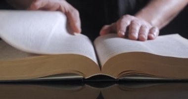 Adam ders kitabının sayfalarını çeviriyor.