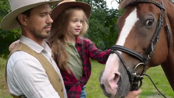 Cowboy en zijn dochter strelen een paard — Stockvideo