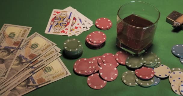 Chips, cards, a glass of whiskey and money are on the green gaming table — Stock Video