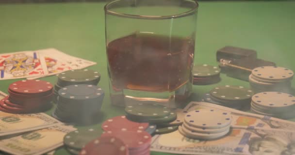 Chips, cards, a glass of whiskey and money are on the green gaming table — Stock Video