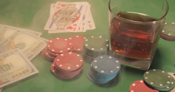 Chips, cards, a glass of whiskey and money are on the green gaming table — Stock Video