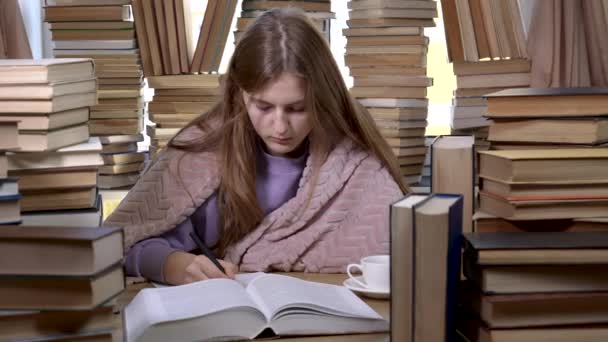 Una chica lee un libro en la biblioteca — Vídeos de Stock