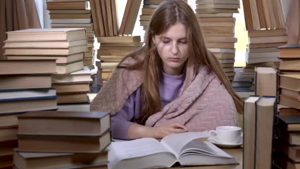 Dziewczyna czyta książkę w bibliotece. — Wideo stockowe