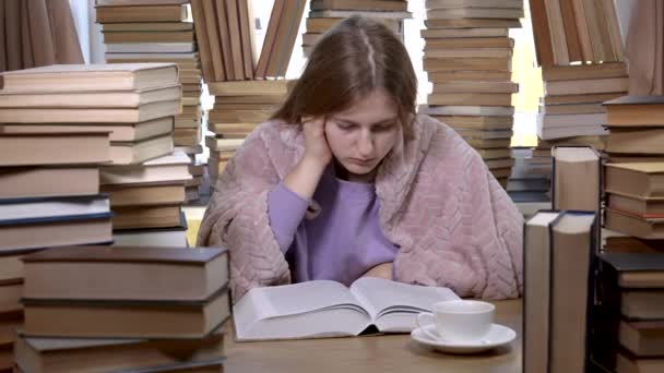 Una chica lee un libro en la biblioteca — Vídeo de stock