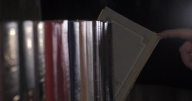 Bir adamın eli doğru kitabı arıyor kitap koleksiyonu arasında.