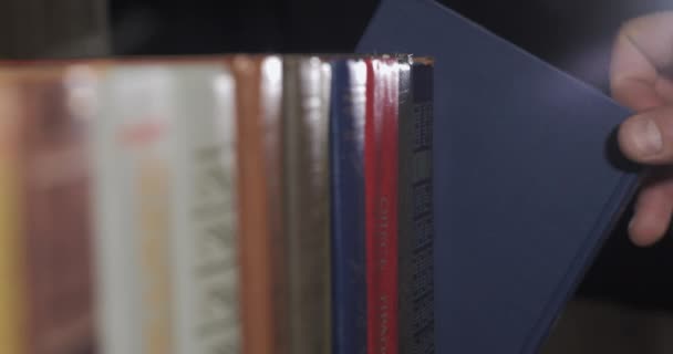 A mans hand is looking for the right book among a collection of volumes — Stock Video