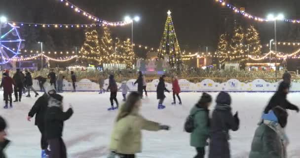 People skate on ice rink at winter night in open air — стокове відео
