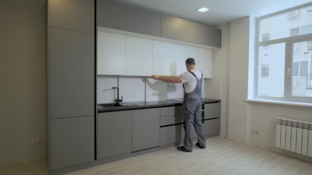 Der Bauherr überprüft die Maße und die Qualität der Montage der Küchenmöbelkonstruktion — Stockvideo