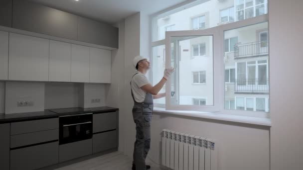 Un constructor en uniforme comprueba el tamaño y la calidad de la instalación de ventanas en un nuevo apartamento — Vídeo de stock