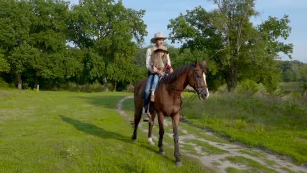 Cowboy e sua figlia a cavallo su un prato della foresta — Video Stock