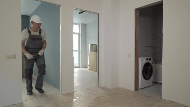 Un constructor en uniforme de trabajo comprueba el tamaño y la calidad de las puertas de un nuevo apartamento — Vídeo de stock