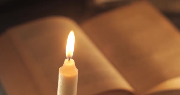 Una vela ardiente y un libro antiguo — Vídeo de stock