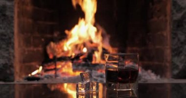 Yangının arka planında viski ya da konyak olan bir bardak.