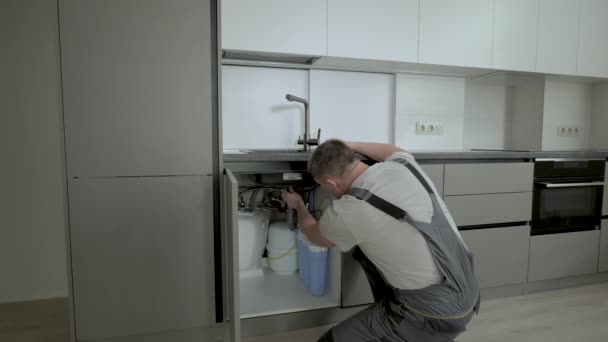 Άντρας υδραυλικός στερέωση σωλήνες κάτω από το νεροχύτη στην κουζίνα — Αρχείο Βίντεο