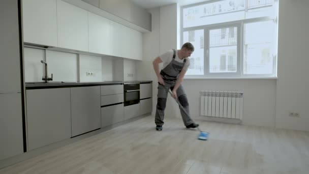 Un constructeur en uniforme lave le sol dans un nouvel appartement — Video