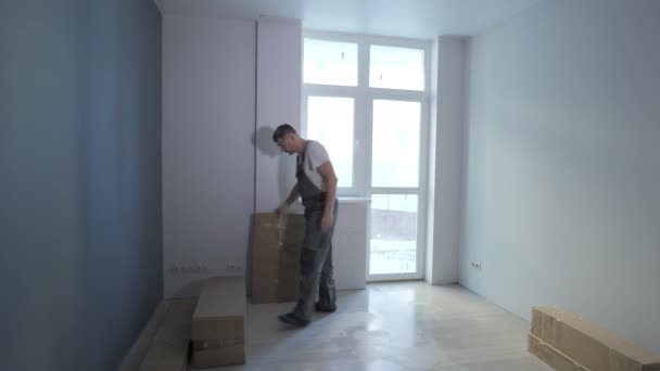 Trabajador mueve cajas en un nuevo apartamento — Vídeos de Stock