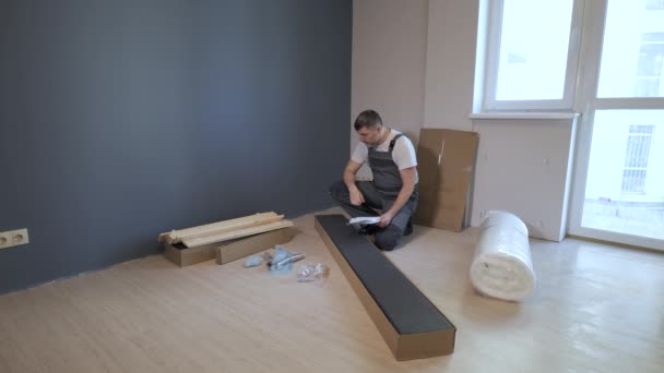 De werknemer kijkt naar de instructies voor het monteren van meubelen — Stockvideo