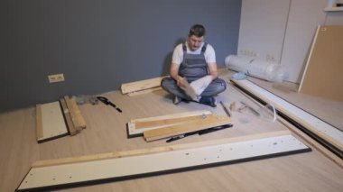 Mobilyaları monte etmeden önce talimatları öğrenen işçi