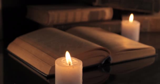 Uma vela ardente e um livro antigo — Vídeo de Stock