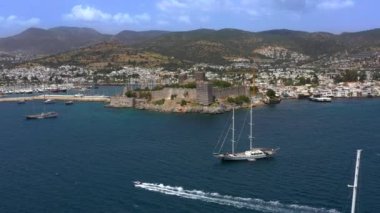 Türkiye 'deki Bodrum Kalesi' nin havadan görüntüsü. İnsansız hava aracı deniz körfezi ve kalenin üzerinde uçuyor. Bodrum, Türk Rivierası 'nda popüler bir turizm beldesi.