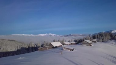 Flight over wooden houses in mountains in winter. Beautiful landscape. Aerial view