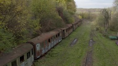 Aerial view of a retro train on the railway tracks. Drone flight over the old rusty wagons of the narrow gauge railway