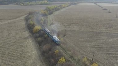 Aerial view of the train rides on the railroad. Drone flight over the locomotive and carriages of the narrow gauge railway.