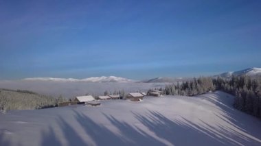 Flight over wooden houses in mountains in winter. Beautiful landscape. Aerial view