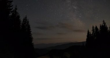 Time lapse of moving clouds and stars over the mountains in the night sky. Starry night background. Epic video 4K
