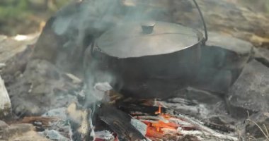 Kettle on a bonfire in the forest. Preparing food on campfire in wild camping. Outdoor recreation concept and Travel in the forest. close-up
