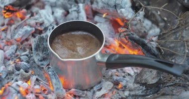 Preparing coffee on coals in a coffee maker. Brewing coffee on a campfire in nature, close-up. Travel concept. 4k